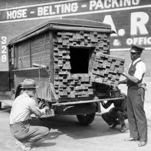 Obrázek 'Federalni agent prohledava  drevo nakladak  behem prohibice. 1926'