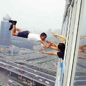 Obrázek 'man-hanging-from-tall-building-window'