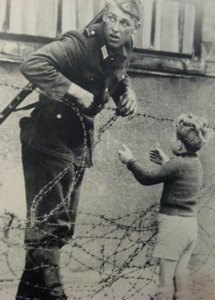 Obrázek An East German soldier helps a boy over the barbed wire on the East-West border