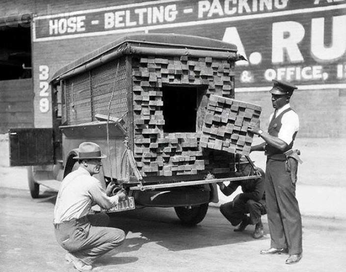 Obrázek Federalni agent prohledava  drevo nakladak  behem prohibice. 1926