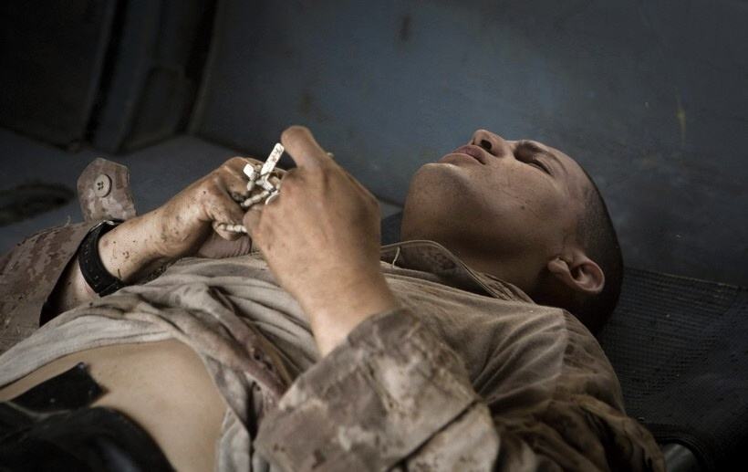 Obrázek Foto tyzdna - Afganistan - Raneny americky vojak zviera v ruke ruzenec pocas osetrenia na palube helikoptery