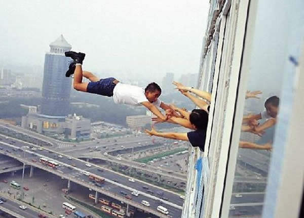 Obrázek man-hanging-from-tall-building-window